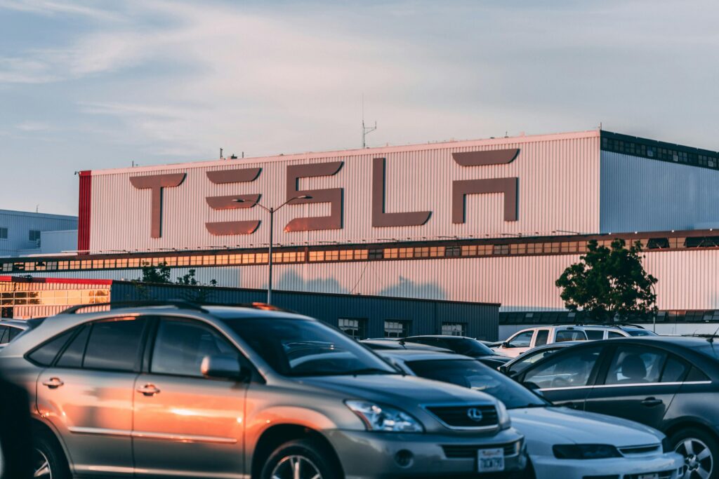 Tsla stock price prediction 2025 2030 Tesla factory with parked cars during sunset, showcasing modern automotive industry vibes.