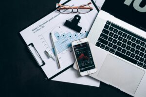 Home Top view of financial documents, laptop, and smartphone displaying stock market data.